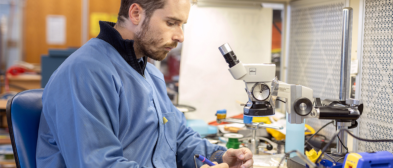 A photo of a student soldering electronics in a lab at Iowa